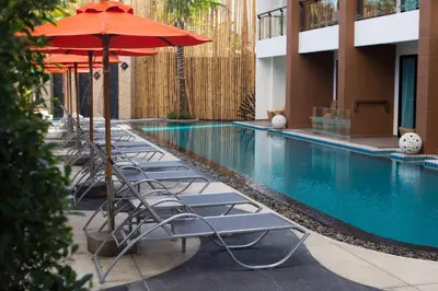 a row of chairs with umbrellas next to a swimming pool at The Beach Residence Kata in Kata Beach