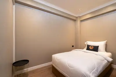 a bedroom with a white bed with a black pillow at RQ Timeless Phuket Old Town in Phuket Town