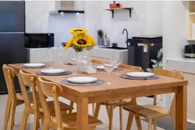 a wooden table with chairs and a vase of yellow flowers at Patong Center lucky home in Patong Beach