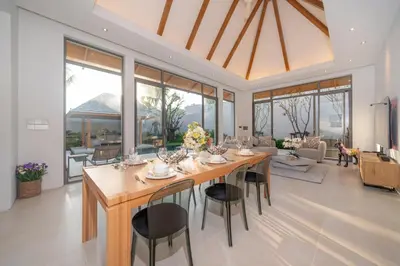 a dining room with a large wooden table and chairs at Thai-Balinese Pool Villa Anchan Indigo16 in Ban Phru Champa