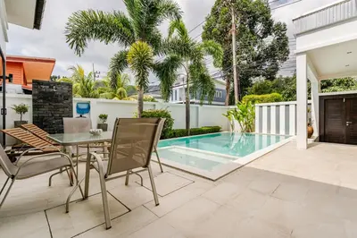 a patio with a table and chairs next to a swimming pool at Baan Araya by Villacarte in Ban Saiyuan (1)