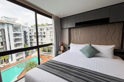 a bedroom with a large bed and a large window at 2 BR Apt Pool View - CTG B507-8 in Kamala Beach