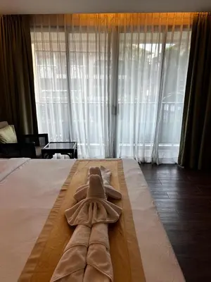 a large bed with a robe on top of it at The Beach Condotel Kata in Kata Beach