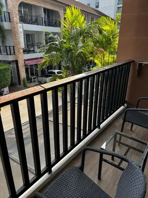 a balcony with two chairs and trees and a building at The Beach Condotel Kata in Kata Beach