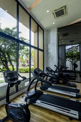 a gym with several cardio machines in a room with windows at Mida Grande Ocean View in Surin Beach