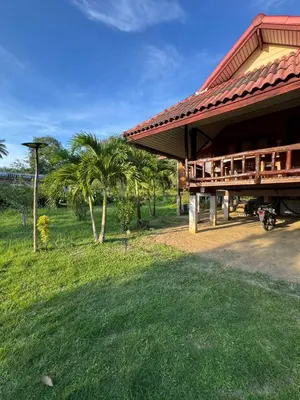 a building with a red roof and some palm trees at Family house in Ban Laem Sai