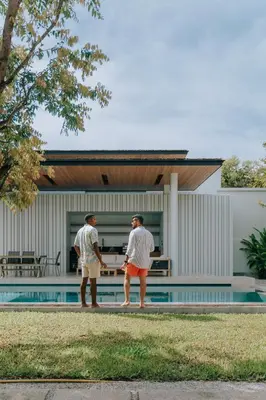 two men standing by a swimming pool next to a house at Botanica Foresta B09 in Ban Phru Champa