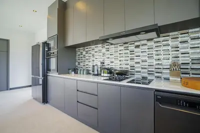 a kitchen with white cabinets and a stove top oven at Camellia Pool VillaNear Nai Harn And Rawai Beach in Ban Saiyuan (1)