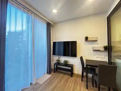 a living room with a dining room table and a television at Cozy studio 1 bdr Golf view in Laguna Phuket
