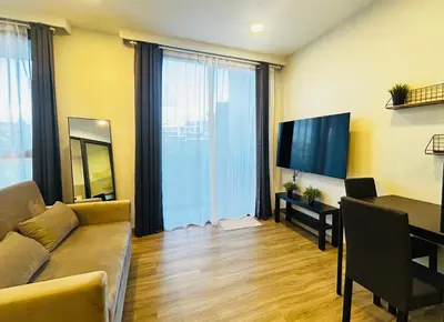 a living room with a couch and a table and a television at Cozy studio 1 bdr Golf view in Laguna Phuket