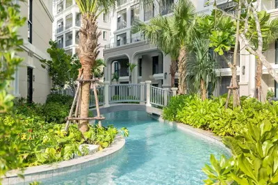 a swimming pool in front of a building with palm trees at The Title Legendary D-605 1 BR Bangtao Beach in Bang Tao Beach