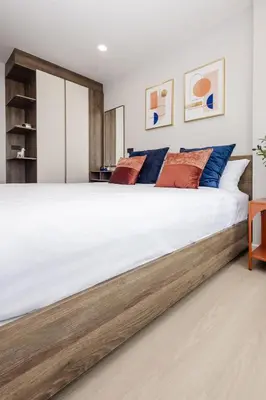 a bedroom with a large white bed with blue and orange pillows at The SPACE Apartment 614 in Ban Thalat Choeng Thale