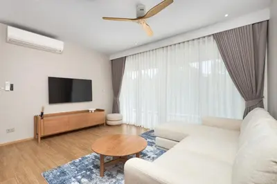 a living room with a white couch and a flat screen tv at Laguna BeachSide Bang Tao by My Home Phuket in Bang Tao Beach