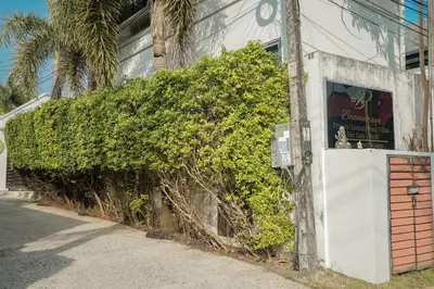 a green hedge next to a building with a sign at Villa Heaven - Peaceful 3 Bedroom Private Pool Villa in Ban Kata