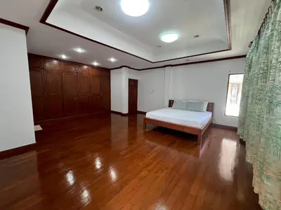 a large room with a bed and a wooden floor at Villa Vasu in Ban Bang Khu