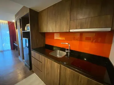 a kitchen with a sink and wooden cabinets at The Beach Condotel Kata in Kata Beach