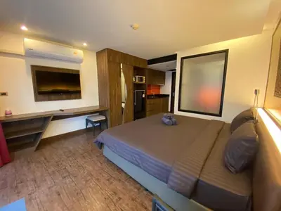 a bedroom with a bed and a desk and a television at The Beach Condotel Kata in Kata Beach