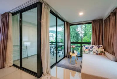 a bedroom with a bed and a balcony with a table at the Kris Bangtao Phuket not in laguna area in Laguna Phuket