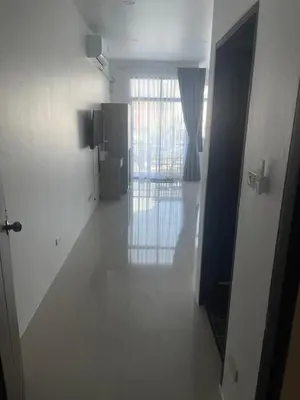 a hallway with a door to a room with a window at Nai-harn Apartments in Phuket Town