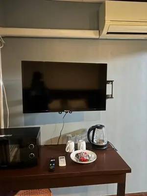 a table with a plate of food and a tv on a wall at Milos House in Ban Kata