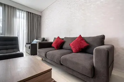 a living room with a gray couch and red pillows at 1Bdr in Cassia Residence Laguna in Laguna Phuket