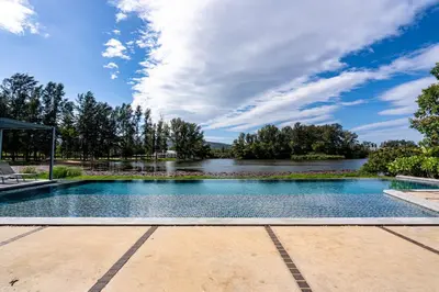 a swimming pool with a river in the background at 1Bdr in Cassia Residence Laguna in Laguna Phuket