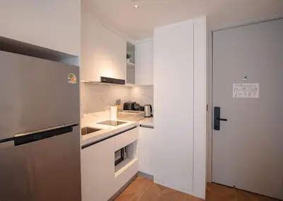 a white kitchen with a sink and a refrigerator at Kora Beachfront 240 One Bedroom Apartment Phuket in Phuket Town