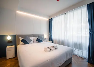 a bedroom with a large white bed with blue curtains at Kora Beachfront 240 One Bedroom Apartment Phuket in Phuket Town