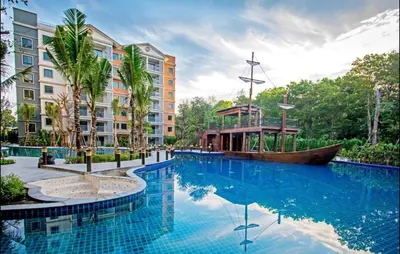 a large swimming pool with a boat in front of a building at Cozy 1BR Tropical View at Title in Nai Yang Beach