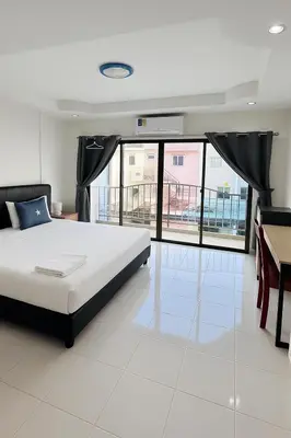 a bedroom with a bed and a table and windows at Smile room 21 in Patong Beach