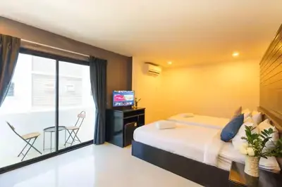 a bedroom with a bed and a balcony with a television at AP Apartment in Kathu