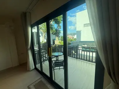 a room with a balcony with a table and glass doors at RK Boutique rooms in Patong Beach