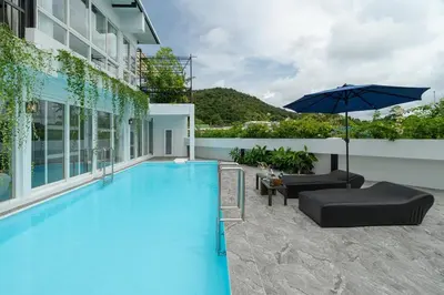 a large swimming pool with an umbrella and chairs at The Garden Escape Villa, Private Tropical Hideaway in Rawai Beach