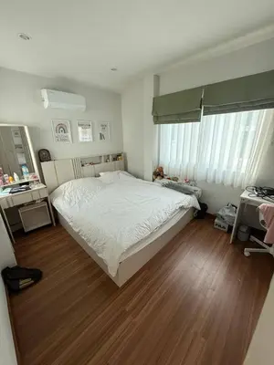a bedroom with a white bed and a wooden floor at La Perla Residence in Ban Phak Chit