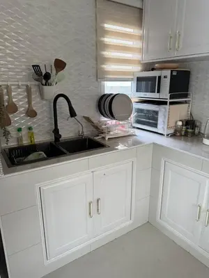 a white kitchen with a sink and a microwave at La Perla Residence in Ban Phak Chit