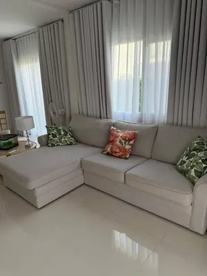 a living room with a couch with pillows on it at La Perla Residence in Ban Phak Chit