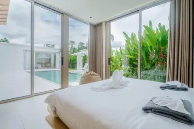 a bedroom with a bed and a large window at Brand New Asherah Pool Villa next to Bangtao Beach VVPHU52 in Ban Riang