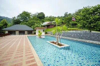 a swimming pool with two palm trees next to a building at B204 Banjong Studio 3 Minutes To Nai Harn Beach in Rawai Beach