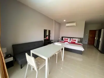 a bedroom with a bed and a white table and chairs at Chernin Apartment Suites in Ban Saiyuan (1)