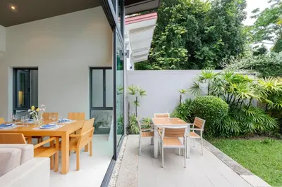 an outdoor patio with a wooden table and chairs at Tropic Escape @ Baan Wana Phuket in Thalang