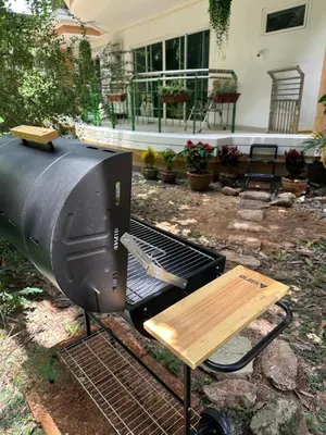 a grill with a wooden table next to a bench at Roomy renovated Apartments in Phuket in Ban Sam Kong