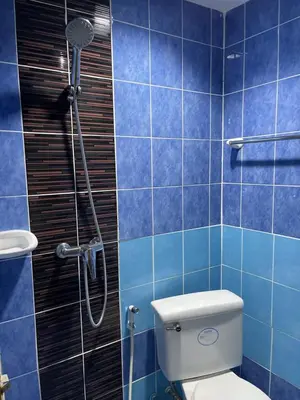 a blue tiled bathroom with a toilet and a shower at Rungtawan Hostel in Karon Beach