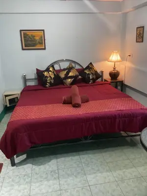 a bedroom with a large bed with a red comforter at Rungtawan Hostel in Karon Beach