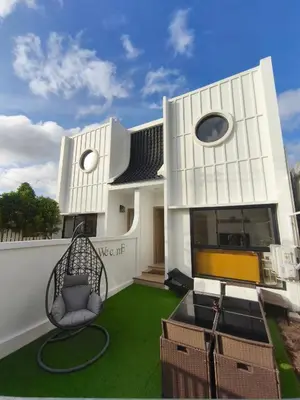 a white house with a chair on a lawn at PS Guesthouse in Kathu