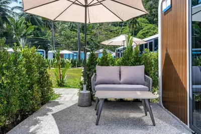 a chair sitting under an umbrella on a patio at Apple House Phuket with cozy terrace Pool & beach in Ban Lum Fuang