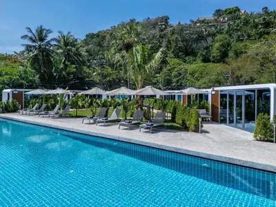 a resort swimming pool with lounge chairs and umbrellas at Apple House Phuket with cozy terrace Pool & beach in Ban Lum Fuang