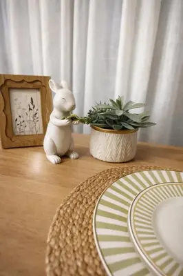 a white rabbit sitting on a table next to a plant at New 1BR Condo, walk to Bang Tao Beach in Laguna Phuket