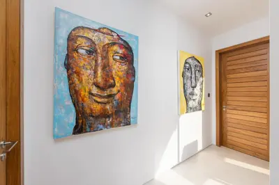 a hallway with two paintings of a face on the wall at Modern 3BR Villa Kaimana with Private Pool in Ban Phru Champa