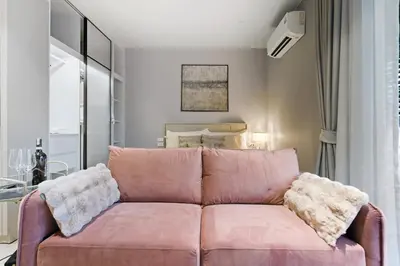 a living room with a pink couch and a bed at Studio with a terrace in The Title Legendary in Bang Tao Beach