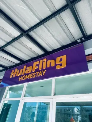 a purple and yellow sign hanging from a building at HulaFling Homestay in Ban Bo Han
